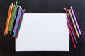 Blank paper list with coloured pencils on balck background.