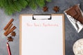 Blank paper with new year`s resolutions title, coffee, bar of chocolate and red pencil on grey table. Flat lay. Top view Royalty Free Stock Photo