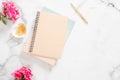 Blank paper notebook, pink flowers, golden stationery on marble background. Flat lay, top view feminine home office desk Royalty Free Stock Photo