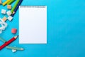 Blank paper notepad mockup with school supplies on blue background. Flat lay, top view, copy space. Back to school. Royalty Free Stock Photo