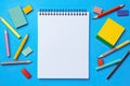 Blank paper notepad mockup with school supplies on blue background. Flat lay, top view, copy space. Back to school.