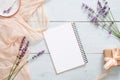 Blank paper notepad, pastel pink color blanket, lavender flowers and gift box on rustic blue wooden background. Top view, tender