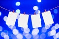 Blank paper or photo frames hanging on the red striped rope. Blurred defocused blue color lights background, Template Royalty Free Stock Photo