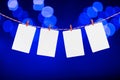 Blank paper or photo frames hanging on the red striped rope. Blurred defocused blue color lights background, Template