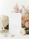 Blank paper sheet standing on a table with flowers, wedding sign mockup in elegant feminine style