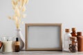 Blank photo frame, different bottles and decor elements on wooden table