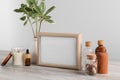 Blank photo frame, different bottles and decor elements on wooden table