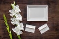 Blank photo frame near flower gladiolus on dark wooden background top view mockup Royalty Free Stock Photo