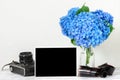 Blank photo frame and vintage retro camera with beautiful bouquet of blue hydrangea flowers and rolled film Royalty Free Stock Photo