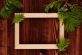 Blank photo wood frame and young green leaves on vintage brown wooden board. Decorative summer background with copy space, top vie Royalty Free Stock Photo