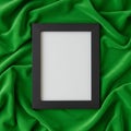 A blank picture frame with a black border is placed on draped green fabric. The frame Royalty Free Stock Photo