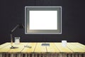 Blank picture frame on black wall with wooden table with lamp an Royalty Free Stock Photo