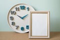 Blank picture frame with clock on brown shelf. mint wall background. copy space Royalty Free Stock Photo