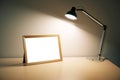 Blank picture frame with lamp on wooden table Royalty Free Stock Photo