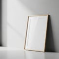 A blank picture frame with a light wood border, leaning against a Royalty Free Stock Photo