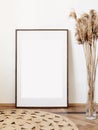 Blank picture frame mockup on white wall. Artwork in minimal interior design. View of modern boho style interior with canvas