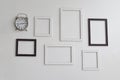 Blank picture frames and clock on white cement wall Royalty Free Stock Photo