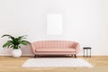 Blank picture or poster mockup.Pink sofa with black coffee table and plant in bright living room with white wall and wooden floor.