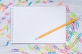 Blank piece of paper in a cage, on the table with a pencil surrounded by multi-colored clips Royalty Free Stock Photo