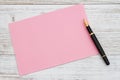 Blank pink greeting card with pen on wood