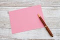 Blank pink greeting card with pen on wood