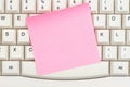 Blank pink sticky note on a gray computer keyboard Royalty Free Stock Photo