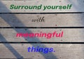 Inspirational quote - Surround yourself with meaningful things. A sign on a rustic wooden wall with colorful text message.