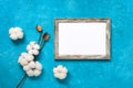 Blank portrait frame mock up and cotton flowers on a blue grunge background. Template for your design. Top view, flat lay, copy