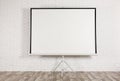 Blank projection screen near white brick wall indoors. Space for design