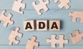 Blank puzzles and wooden cubes with the text ADA Americans with Disabilities Act lie on a light blue background Royalty Free Stock Photo