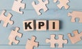 Blank puzzles and wooden cubes with the text KPI lie on a light blue background Royalty Free Stock Photo