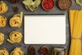 Blank recipe book, spices and raw pasta on dark grey table, flat lay. Space for text Royalty Free Stock Photo