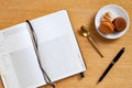 Blank recipe notebook and a pen with brown and white french macaroons in a plate with a golden spoon, oak wood background Royalty Free Stock Photo