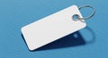 Blank rectangular white key tag with metal ring on a textured blue surface offering a simple copy space Royalty Free Stock Photo