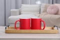 Blank red ceramic mugs on white wooden table. Mockup for design Royalty Free Stock Photo
