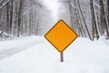 A blank road traffic sign warning of winter driving conditions on a road