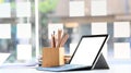 Blank screen computer laptop putting together with stack of books and pencil holder on modern working table. Royalty Free Stock Photo