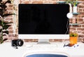Blank screen desktop computer in office room with decorations and copy space. Brick wall on background Royalty Free Stock Photo