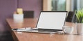 Blank screen laptop computer and a cup of coffee in modern meeting room Royalty Free Stock Photo