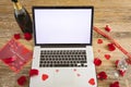 Blank screen on laptop with copy space by champagne bottle and rose petals on table