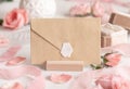 Blank sealed envelope near light pink roses, petals and silk ribbons close up, wedding mockup