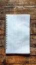 A blank sheet of graph paper from a spiral notebook rests centered on a rustic, dark brown wooden background, perfect for adding Royalty Free Stock Photo