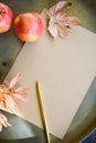 A blank sheet of paper, a golden pen and two ripe apples and dry autumn leaves lie on a metal table. Royalty Free Stock Photo