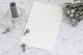 Blank sheet of paper on marble with brunia flowers and candle