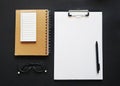 Blank sheet of paper next to pen, notepads, white wired headphones and glasses Royalty Free Stock Photo