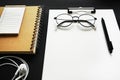 Blank sheet of paper next to pen, notepads, white wired headphones and glasses Royalty Free Stock Photo