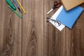 A blank sheet of paper, a notebook, pens, glasses, scissors on a wooden table top, space for text