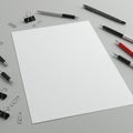 A blank sheet of white paper is centered on a gray surface, surrounded by multiple Royalty Free Stock Photo