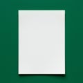 A blank sheet of white paper positioned vertically on a green textured surface. The pap Royalty Free Stock Photo