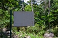 Blank signpost in green forest. Empty sign on metallic pillar in tropical rainforest. Hiking in jungle forest banner template